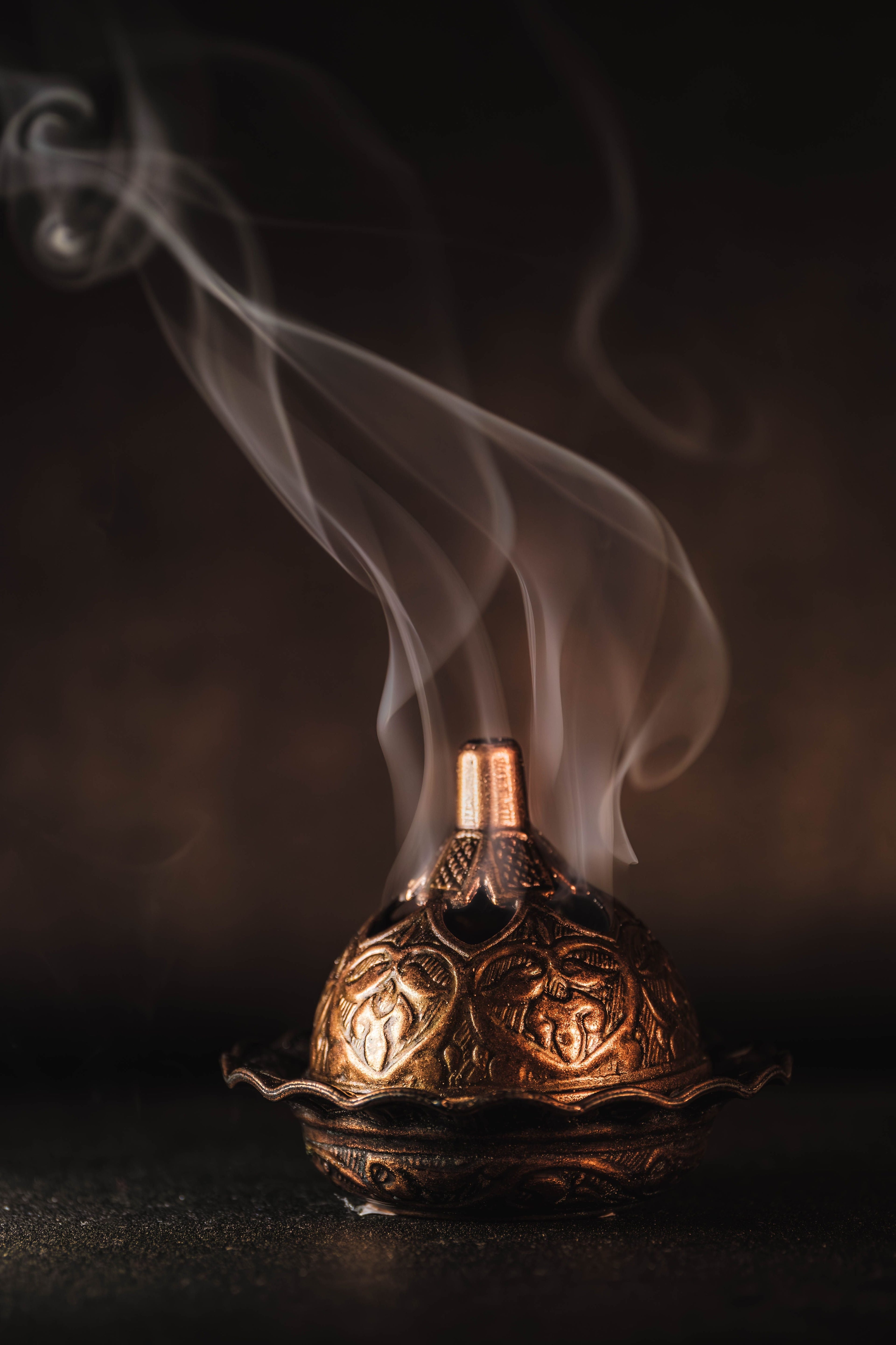 Oud collection — smoke rising from an engraved bakhoor incense burner