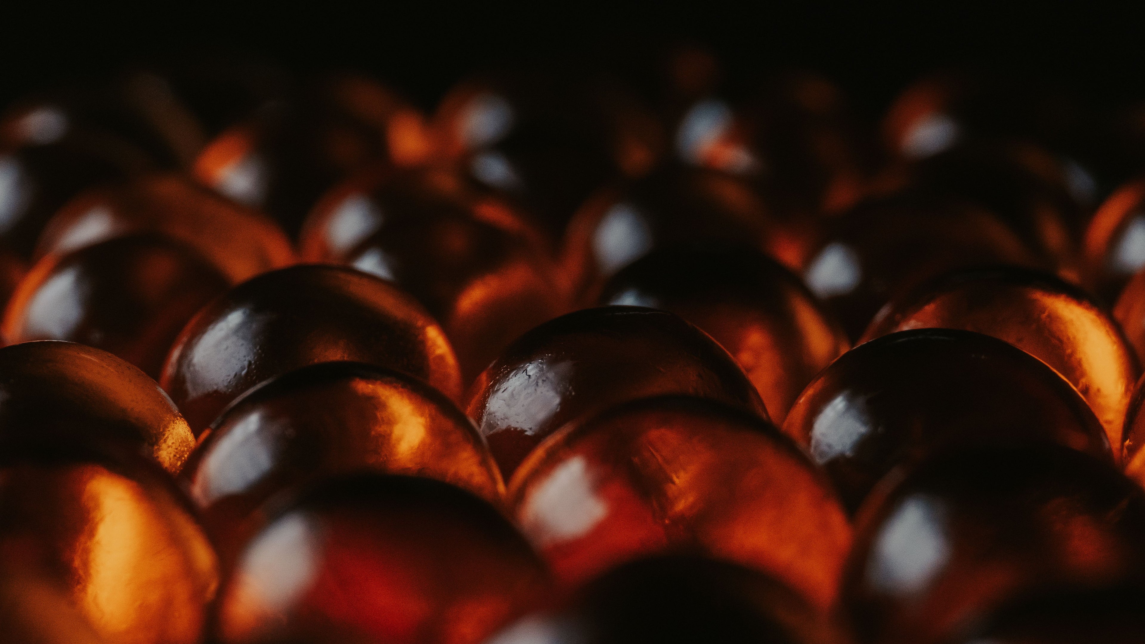 Sweet for Him collection — glossy amber spheres glowing in warm light