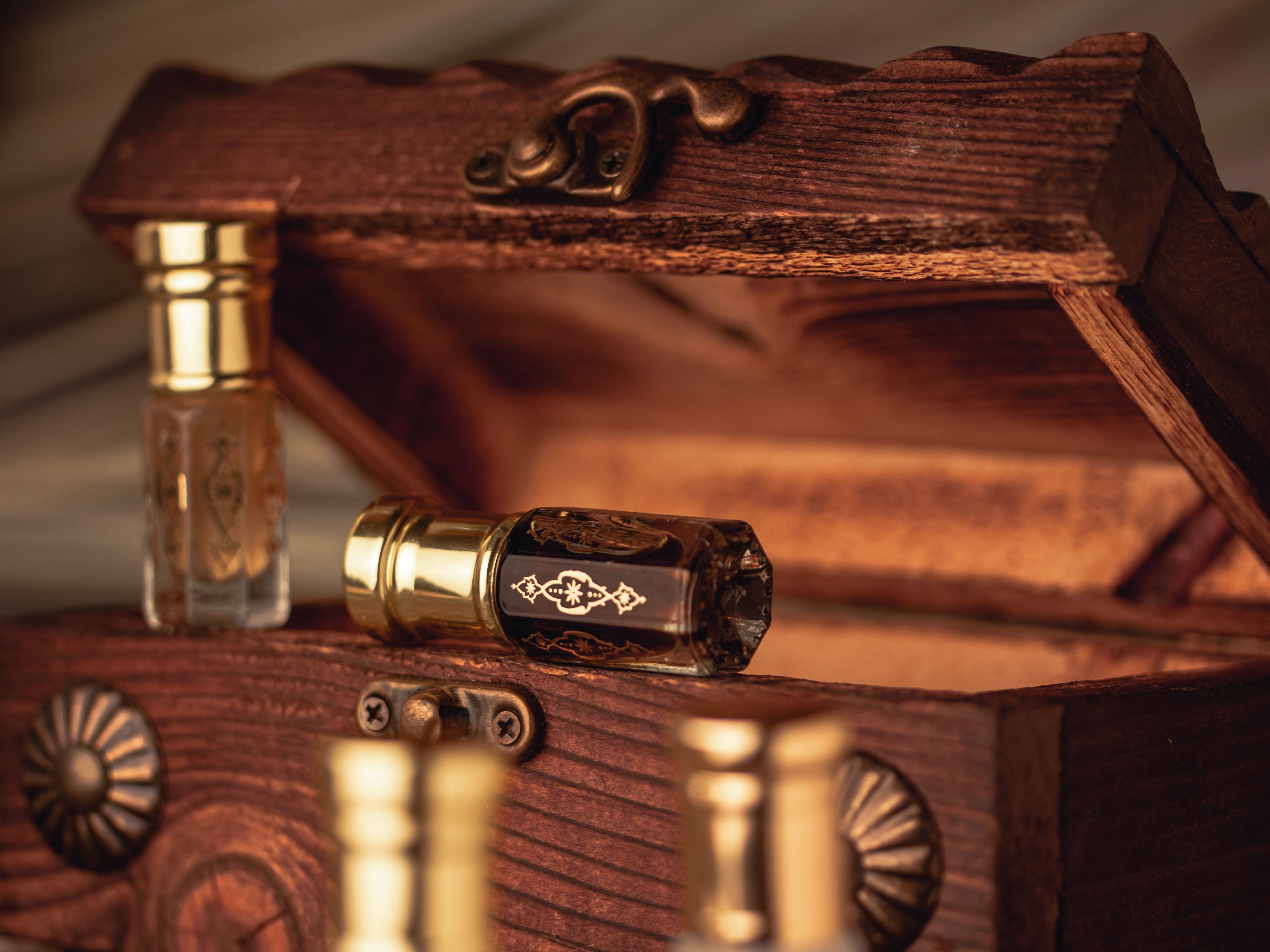 Attar bottles with gold caps in a carved wooden chest — homepage hero